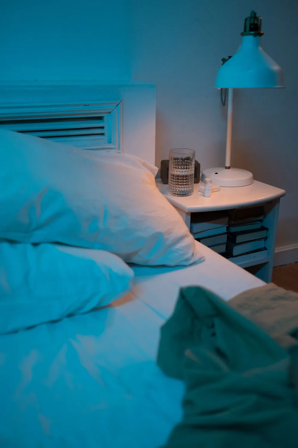 Glass of water and lamp on a bedside table, ready for a night of sweating
